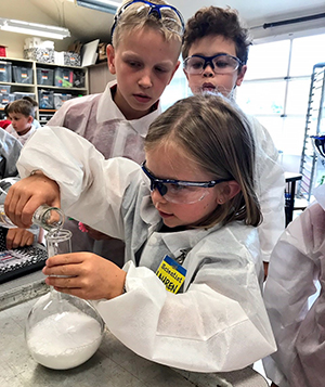 Girl pouring material into beaker for website.jpg Girl pouring material into beaker in classroom